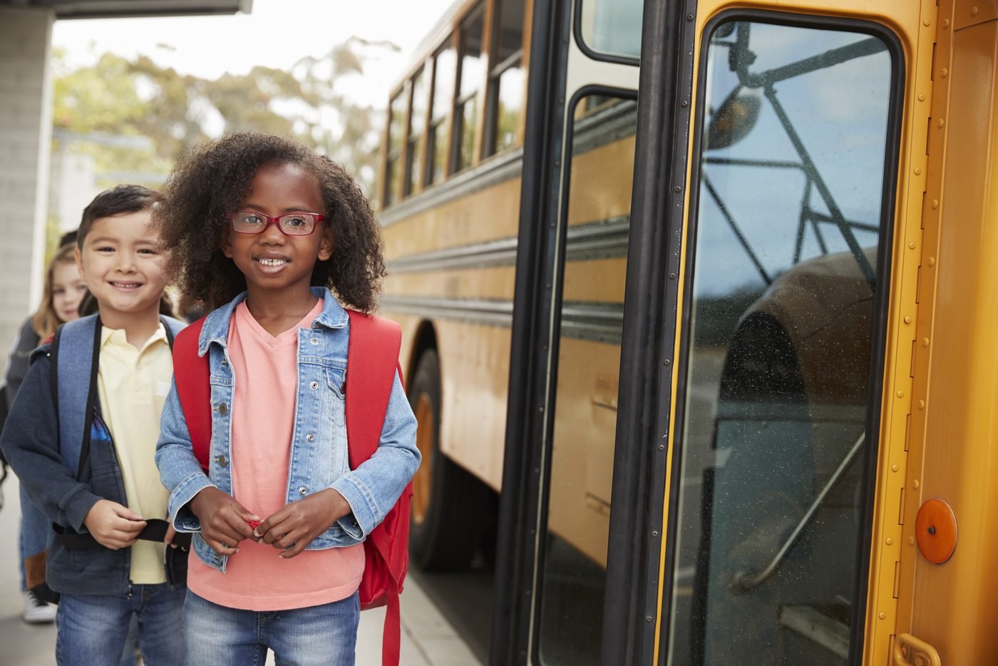 Two students with backpacks boarding a school bus